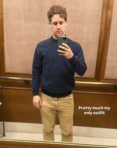 a man standing in front of a mirror taking a selfie with his cell phone