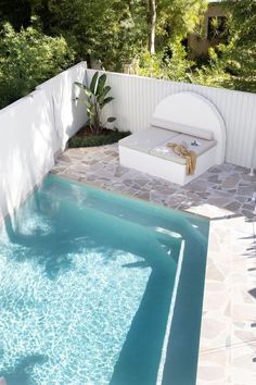 an empty swimming pool in the middle of a backyard with a lounge chair and table