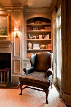 a chair sitting in front of a fire place next to a book shelf filled with books