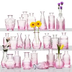 a shelf filled with lots of pink glass vases and flowers on top of it