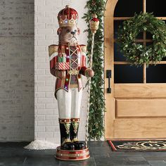 a christmas nutcracker standing in front of a door with wreath on the side