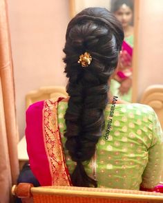 a woman with long hair in a green and pink sari sitting down on a chair