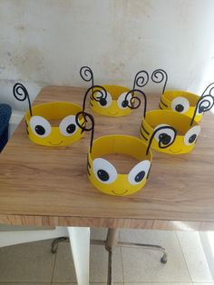 six yellow cups with eyes are sitting on a table