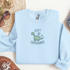 Get your wardrobe and attitude in check with our Embroidered "Get Your Shit Together" Crewneck. Crafted from a comfortable 50/50 cotton-polyester blend, this crewneck is perfect for adding a touch of sass to your everyday style. The standout design features a charming daisy accentuated with the bold and empowering phrase "Get Your Shit Together". Available in a range of sizes from S to 2XL, and in colors including Dark Chocolate, Indigo Blue, Light Blue, Light Pink, Military Green, Navy, Sand, Sport Grey, and White. Please refer to the size chart included in the images for the perfect fit. Please note that colors may vary slightly due to monitor settings. Cotton Tops With Dinosaur Print For Fall, Cotton Top With Dinosaur Print For Fall, Casual Dinosaur Print Tops For Fall, Casual Cotton Sweatshirt With Dinosaur Print, Casual Dinosaur Print Crew Neck Sweatshirt, Sassy Sweatshirts, Funny Dinosaur, Dinosaur Funny, Dinosaur Shirt