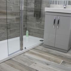 a bathroom with grey tile and wooden flooring