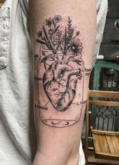 a heart in a jar filled with flowers on the left upper half of the arm