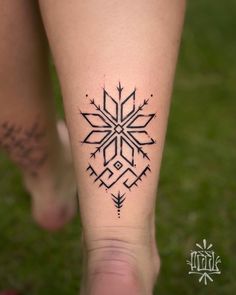 a woman's foot with a tattoo design on the side of her leg that has an arrow and snowflake in it