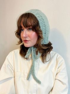 a woman wearing a knitted hat with a scarf around it's brim