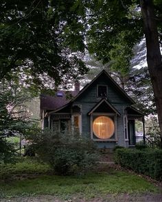 a green house with a round window in the front yard and trees around it at night