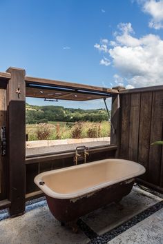 an old bathtub sitting on the side of a wooden wall next to a window