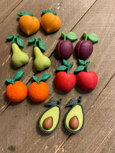 there are many fruits and vegetables made out of fondant on the wooden table together