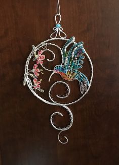 a metal bird hanging from a wooden door with flowers on it's back end