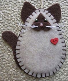 a felt cat ornament with a red heart hanging from it's back