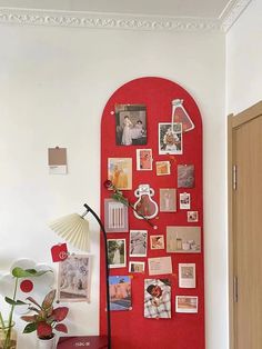 a red bulletin board with pictures on it and a lamp in the corner next to it