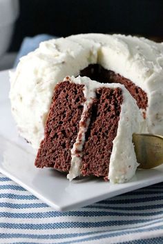 a piece of cake with white frosting on a plate and a fork in it