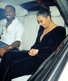 a man and woman sitting in the back of a car looking at their cell phones