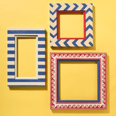 three different colored frames sitting on top of a yellow wall with white and blue stripes