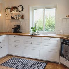 a kitchen with white cabinets and wooden counter tops, along with a rug on the floor