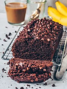 a loaf of chocolate cake sitting on top of a cooling rack next to some bananas