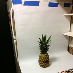 a pineapple sitting on top of a white counter in front of a refrigerator freezer