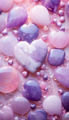 some heart shaped rocks and water droplets on a surface with pink and purple hues