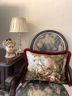 a chair with a pillow sitting on top of it next to a lamp and busturine