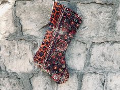 an orange and black patterned stocking hanging on a stone wall