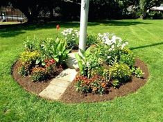 an umbrella is in the middle of a flower bed with grass and flowers around it