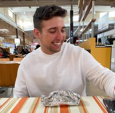 a man sitting at a table with food in front of him and his cell phone