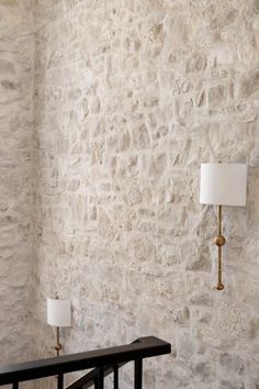 two lamps are next to a stone wall