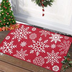 a red rug with white snowflakes on it in front of a christmas tree