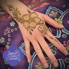 a woman's hand with henna tattoos on it and flowers painted on the palm