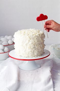 a cake with white frosting and two red hearts on top is being held by a person