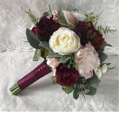 a bridal bouquet with roses and greenery on a lace tableclothed surface