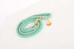 a green rope with a gold charm on it sitting on top of a white surface