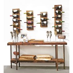 a wooden table topped with bottles of wine next to two shelves filled with books and vases