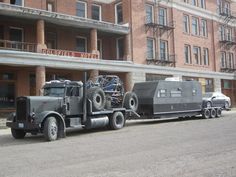 a large truck is parked in front of a building with an army vehicle on the back