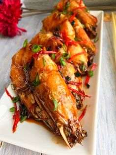 a white plate topped with chicken wings covered in sauce and garnished with green onions