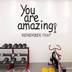 there is a gym with dumbs and exercise equipment in front of the wall that says, you are amazing