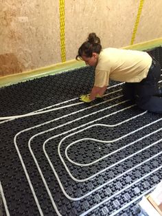 a woman kneeling down on the floor working on an electrical wiring line in a room