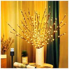 a white vase filled with lots of lights on top of a table next to a plant