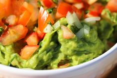 a bowl filled with guacamole and chopped carrots