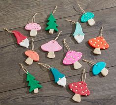 wooden ornaments are hanging from strings on a table with wood planks in the shape of mushrooms and trees