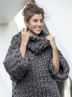 a woman is smiling while wearing a gray knitted sweater and matching pants with her hair in a pony tail