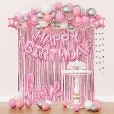 a birthday party with pink and silver balloons, streamers and cake on the table