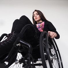 a woman sitting in a wheel chair with her foot on the back of another person's leg