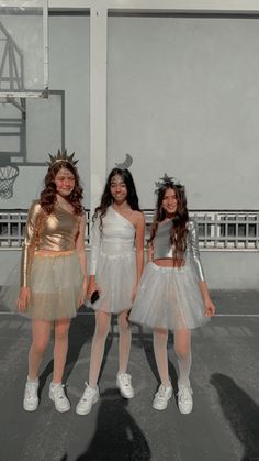 three girls dressed up in costumes standing next to each other with basketball hoop behind them