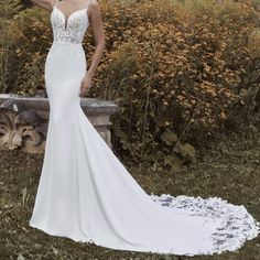 a woman in a white wedding dress standing next to a stone bench with flowers on it