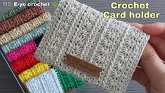 the crochet card holder is made with several colors of yarn and has a brown tag on it