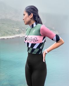 a woman in a wetsuit standing on the beach with her hands on her hips